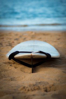 Surfboard with leash on sand with ocean in background